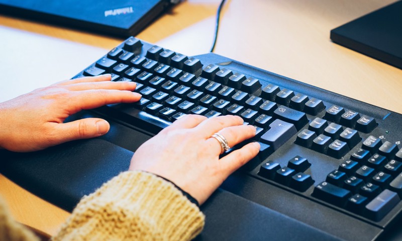 Person i gang med at skrive på et computertastatur Person i gang med at skrive på et computertastatur