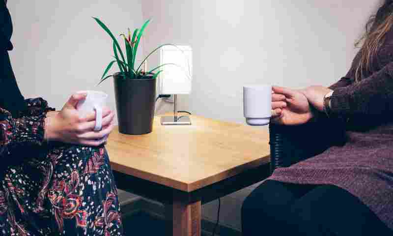 To personer sidder og taler over en kop kaffe